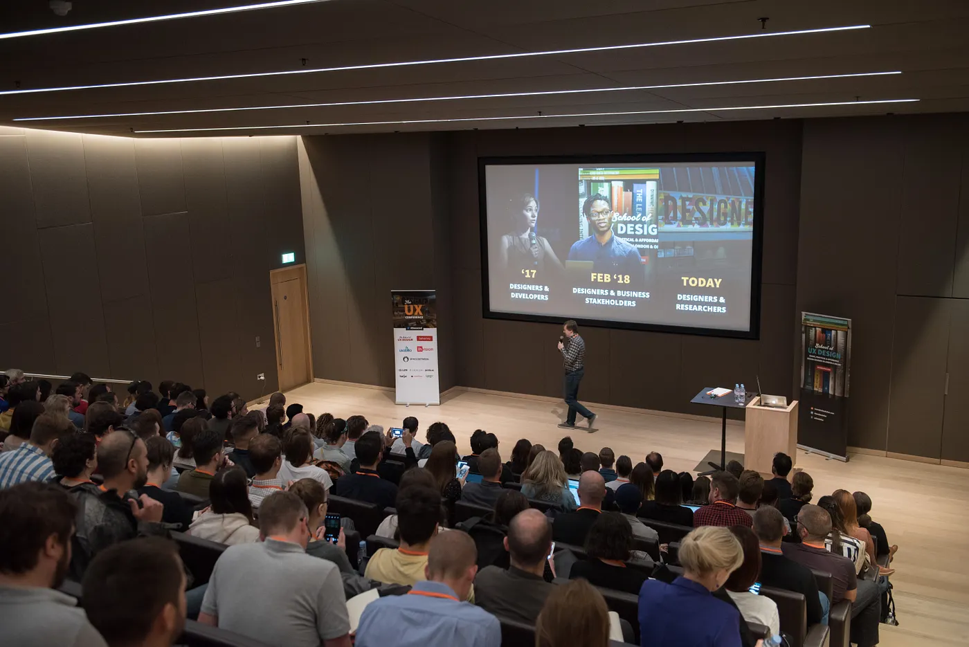 Sergei Golubev presenting on stage at The UX Conference at the Design Museum in 2018, with a full audience